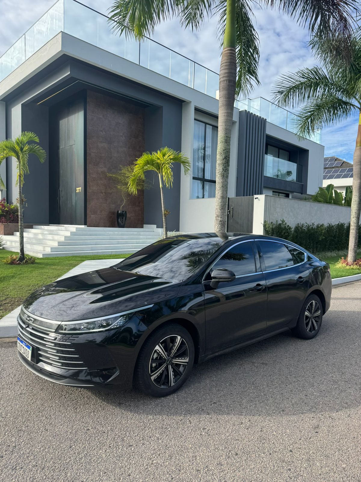 Carro executivo preto em frente a uma casa de alto padrão